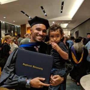 Smiling Saybrook graduate holding son and degree